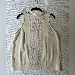 Cream colored embroidered sleeveless blouse.